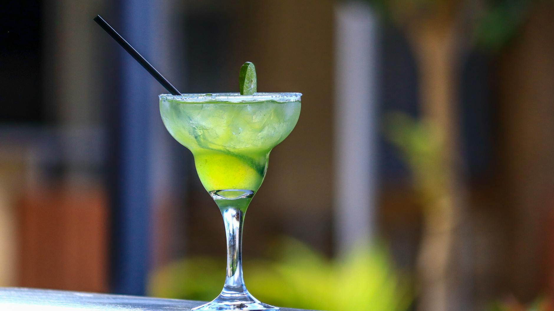 Zielona margarita z limonką i czarną słomką na letnim drinku