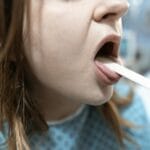 Lekarka bada gardło kobiety po 40. roku życia szpatułką