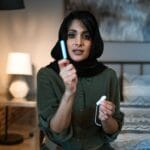 Muzułmanka na łóżku trzyma tampon i tłumaczy zasady higieny intymnej